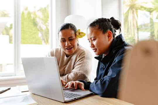 Samoan mum helping teenage daughter with homework using laptop