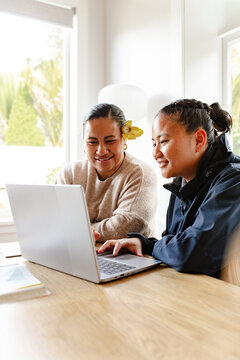 Samoan mum helping teenage daughter with homework using laptop