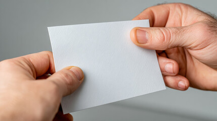 Obraz premium Two hands exchange a blank ballot card before it is cast, tight macro crop with neutral light and copy space. Concept: cooperation, transparency