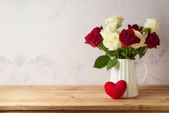 Happy Valentine's day concept with rose flowers and heart shape on wooden table over bright background