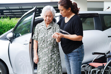 Caregiver help Asian elderly woman disability patient get in her car.