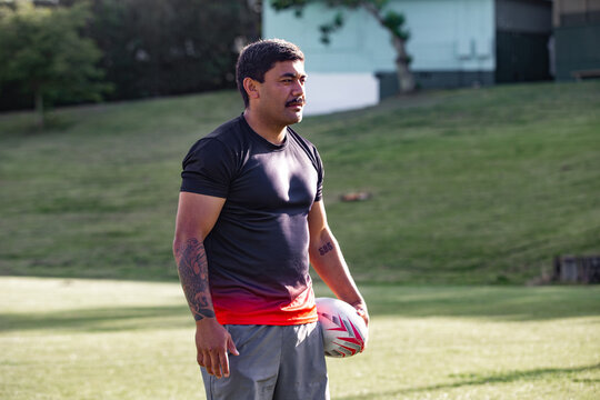Man with a beard holding ruby ball in a sports field