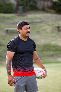 Man with a beard holding ruby ball in a sports field