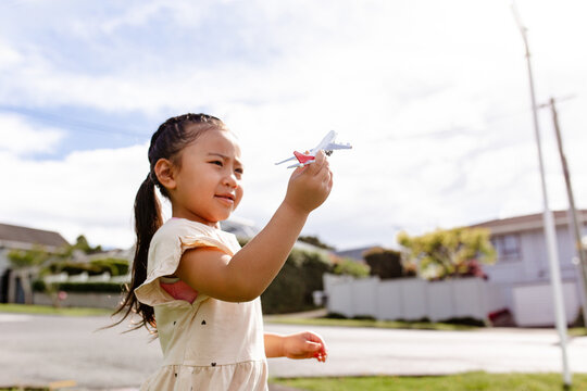 Young Samoan girl holding a toy aeroplane up in the air outdoors - travel concept