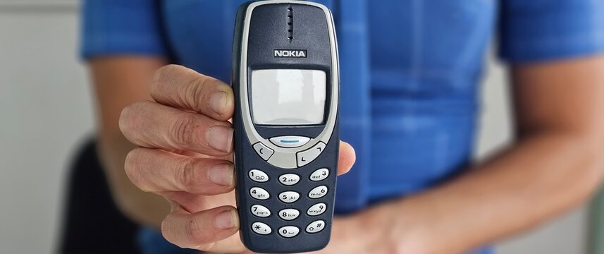 Minsk, Belarus, December 20, 2024 Businesswoman holding vintage phone nokia 3310 in hand concept