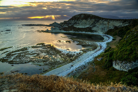 Rugged coastal cliffs at sunset with golden crepuscular rays