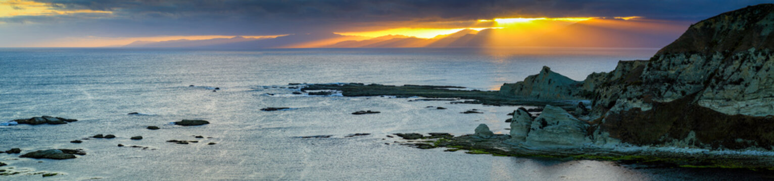 Panorama of rugged coastal jagged rocks at sunset