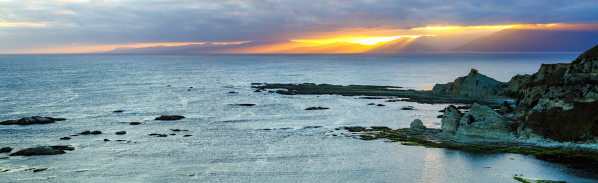 Panorama of rugged jagged coastal rocks at sunset