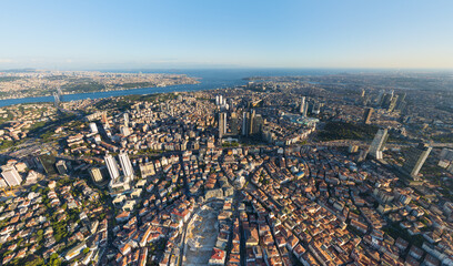 Fototapeta premium Istanbul, Turkey. Panoramic aerial drone view of European city center skyline with modern skyscrapers and Bosphorus Strait at sunset, clear sky. Aerial view