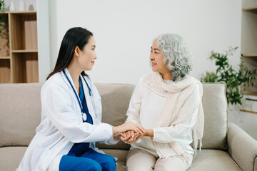 Obraz premium Female doctor supporting elderly woman at home during medical visit. Senior healthcare, home care, patient support, wellness, trust and professional medical assistance concept.