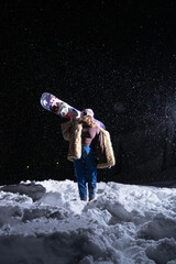 A stylish girl with a snowboard on a black background in a pretentious fur coat © Maxim