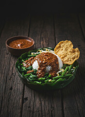Gado Gado Indonesian Salad with Peanut Sauce and Rice Served in Banana Leaf Bowl on Rustic Wood