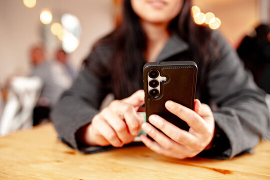 Maori woman sitting at cafe table with a coffee holding her phone
