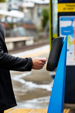 Close-up of hands tapping off at a train station in Auckland