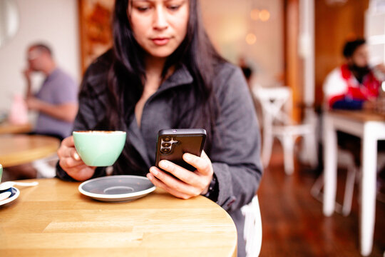 Maori woman sitting at cafe table with a coffee