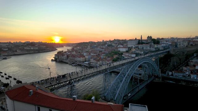 Golden sunset reflecting on the douro river with people crossing the dom luis i bridge in porto