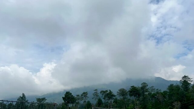 Weather conditions change at the foothills of Mount Merbabu as clear skies gradually shift to foggy and misty scenery, captured in a time-lapse sequence.