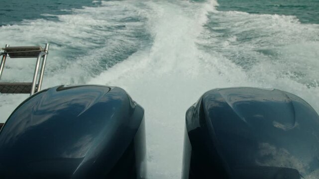 Twin outboard engines of a speedboat creating powerful wake on open sea, dynamic marine transport concept with motion, speed, and travel energy