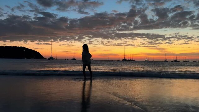 Vibrant after-sunset scene with a glowing orange-red sky. A female silhouette dances energetically on the beach, creating bold social media content against a dramatic tropical twilight backdrop