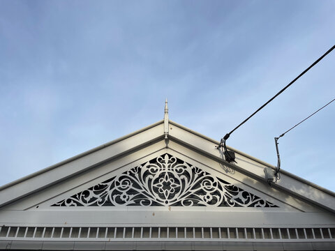 Queenslander House Roof Facade with Power Lines Against Blue Sky