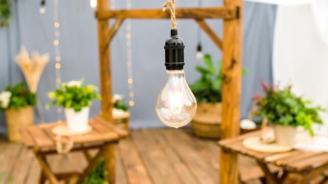 A clear light bulb hangs in the center of the image, set against a wooden backdrop