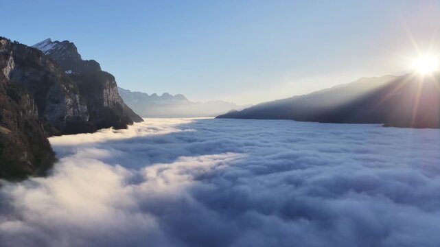 aerial view of alpine valley filled with clouds at sunrise