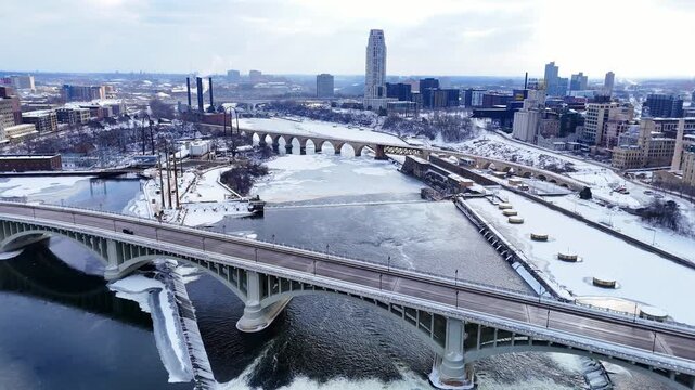 Aerial view of Minneapolis skyline with frozen Mississippi River and arched bridges in winter