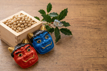 節分の伝統的な豆まきセット、赤鬼と青鬼のお面の置物、福豆、柊鰯の飾りが並ぶ画像素材