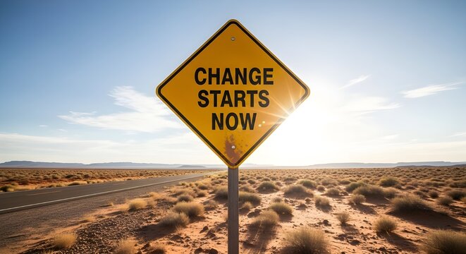 Bright yellow diamond-shaped warning sign emphatically declares that positive change starts right now on a desert road.