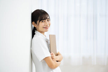 Side View of Smiling Young Woman in White Uniform Holding Clipboard