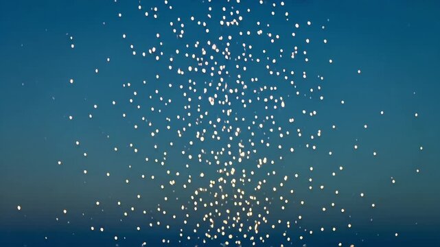 Glowing lanterns flying high in clear blue evening sky