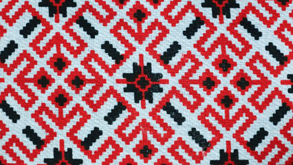 Obraz premium Intricate Mirukser textile pattern showcasing vibrant red and black designs on a white backdrop in natural light