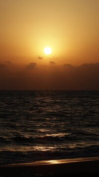 Golden sunset over Chigasaki beach with waves washing on the shore, vertical cinematic footage of Shonan coastline, Japan.