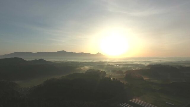 Aerial view of morning mist over rice fields and a rural village with Kirishima Mountain Range at sunrise, Japan. 4K 60p Apple ProRes 422 LT.
