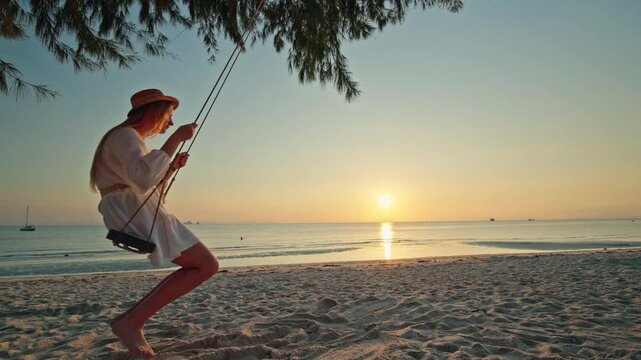 Teenage girl swinging on wooden beach swing at Lipa Noi during sunset and sunrise, silhouette over calm sea with golden reflection, tropical shoreline and peaceful evening mood