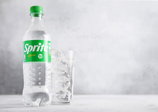 LONDON,UK - JULY 10,2025: Bottle of Sprite Original lemon and lime soda soft drink with glass with ice cubes on light table background.