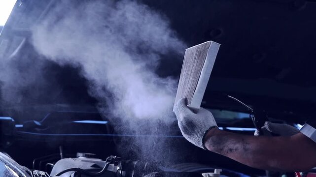 Slow-motion video showing a mechanic performing maintenance and cleaning the car's air filter. Filmed in a studio with a digital camera and edited by a contributor.