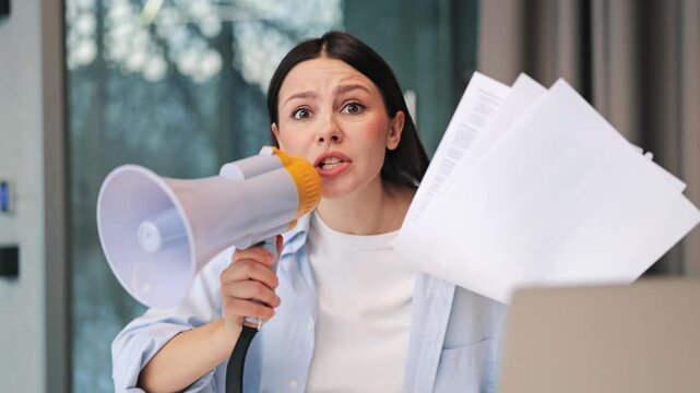 Conveying important news with urgency, a person uses a megaphone to make an announcement. Expressing determination and concern while sharing information.