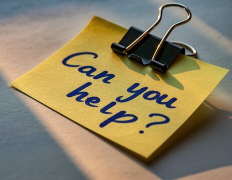 Yellow sticky note with 'can you help' message and black clip