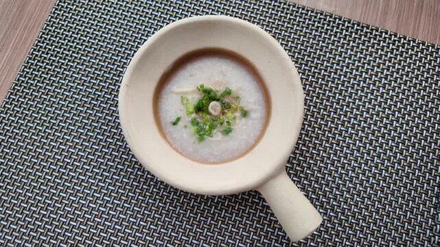 Overhead camera shot of rice porridge in bowl on placemat
