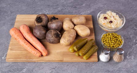 The ingredients for cooking carrots, potatoes, beets, peas and cabbage are on a wooden cutting board.