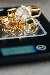 Gold rings, chains, and a watch on a digital scale represent the concept of selling gold for cash, appraisal, and jewelry evaluation in pawnshops and gold exchange services.