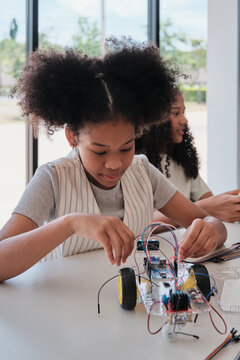 Black student girl robotic mechanical design and electric experiments, learning class in science engineering classroom course, creativity, technology knowledge for kids education of elementary school.