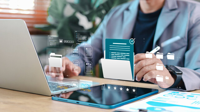 Business professional managing digital documents and folders on tablet and laptop with secure file icons. Concept of document management system, data security, and workflow automation.