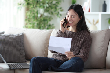 Obraz premium Happy asian woman talking on phone about letter