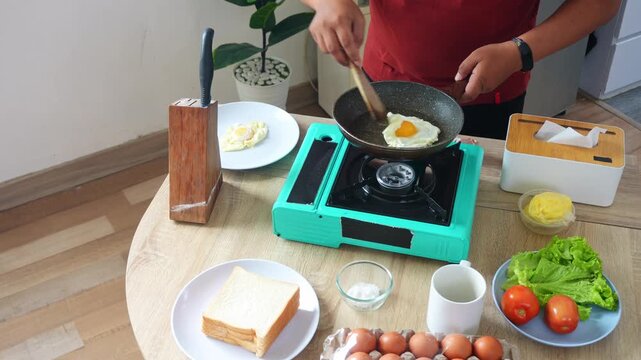 Man skillfully flips side-up egg in frying pan preparing filling for fresh breakfast sandwich