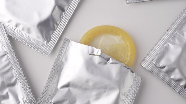 Showing packets of silver colored condoms on a white background.