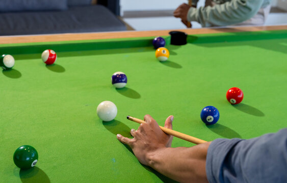 Two adults aiming with cue lining up shot on billiards table in game room, copy space