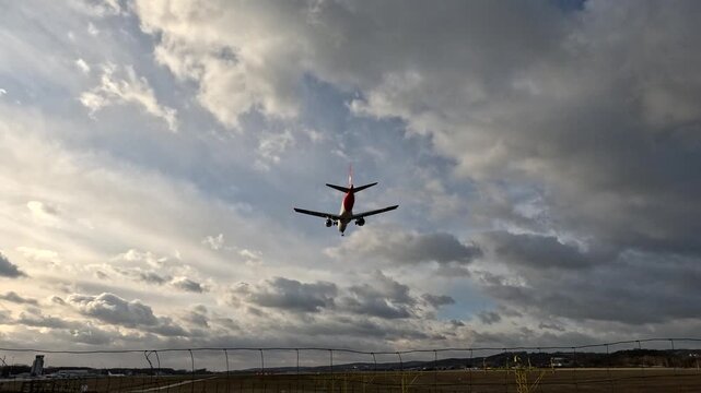 Plane landing at airport with clouds in the background