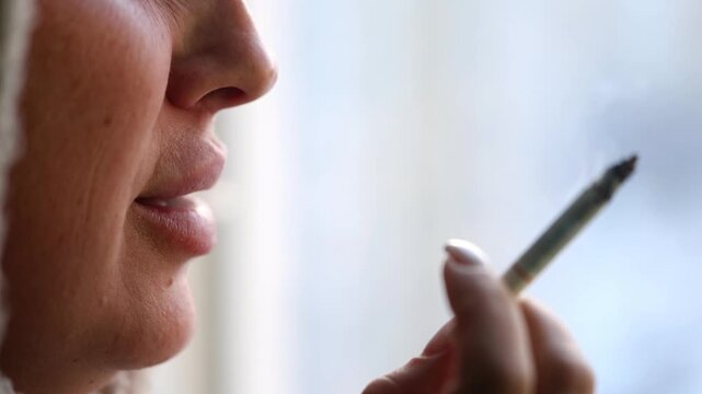 A woman smokes a cigarette and blows smoke out of her mouth. A woman smokes.
